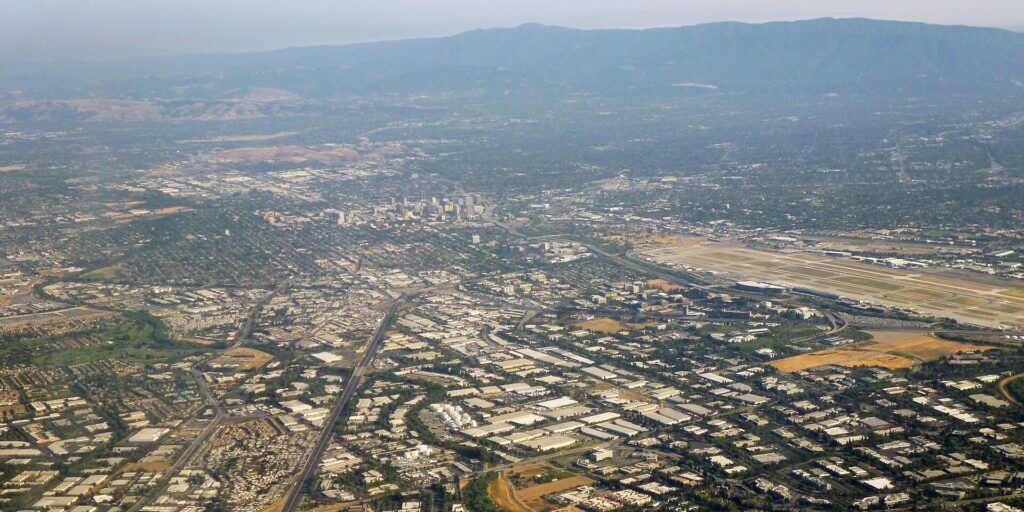 Aerial view of Silicon Valley's urban landscape with highways, industrial parks, and downtown San Jose in the distance